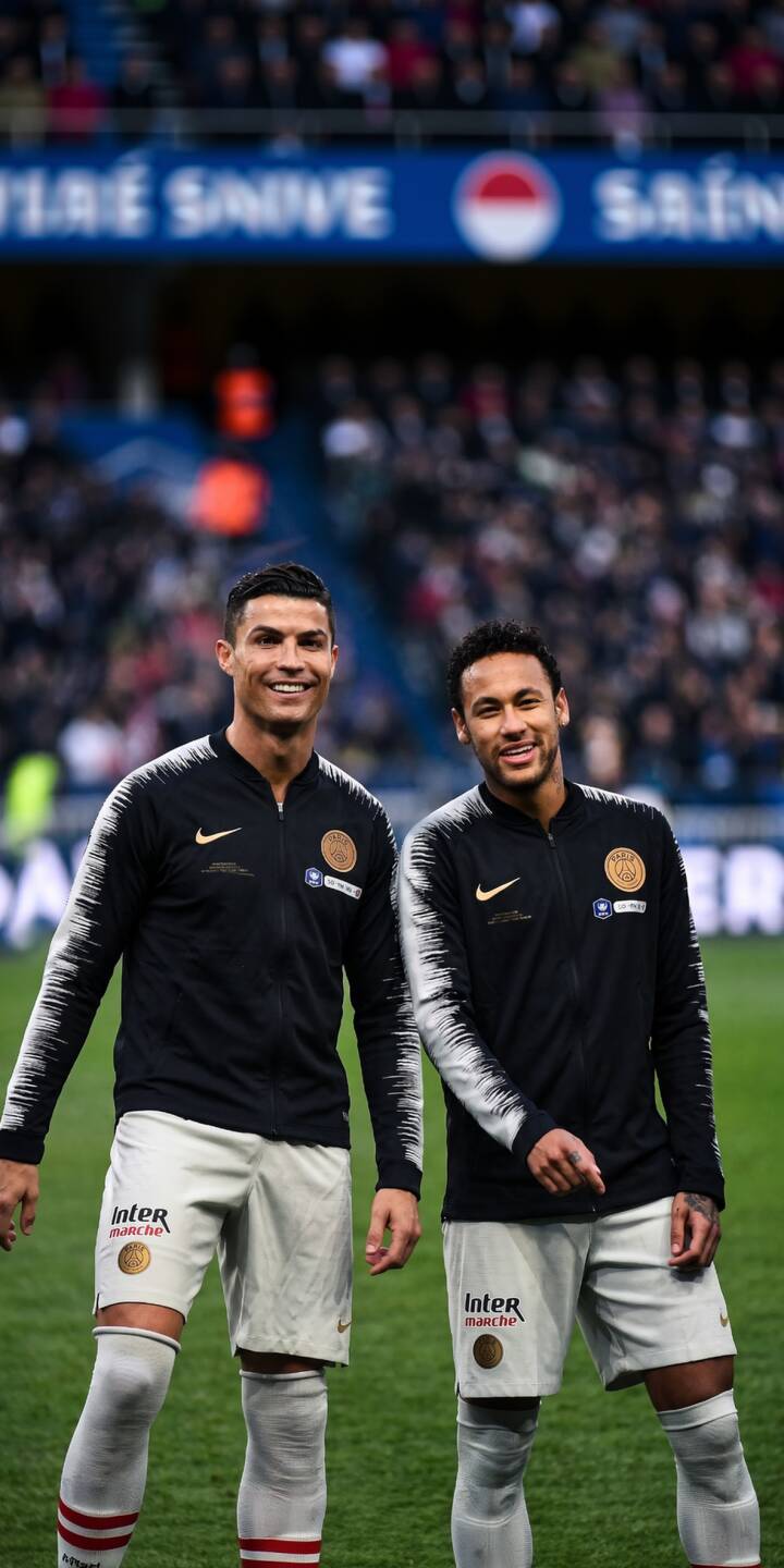 Smiling broadly, Cristiano Ronaldo and Neymar Jr. pose together on the vibrant green pitch in this stunning 4K wallpaper. This dynamic duo wallpaper, perfect for iPhone, features both football stars in matching dark track jackets and white shorts. | football stadium iphone ronaldo soccer wallpaper neymar cristiano ronaldo mobile 4k wallpaper hd wallpaper athletes Smiling broadly, Cristiano Ronaldo and Neymar Jr. pose together on the vibrant green pitch in this stunning 4K wallpaper. This dynamic duo wallpaper, perfect for iPhone, features both football stars in matching dark track jackets and white shorts.