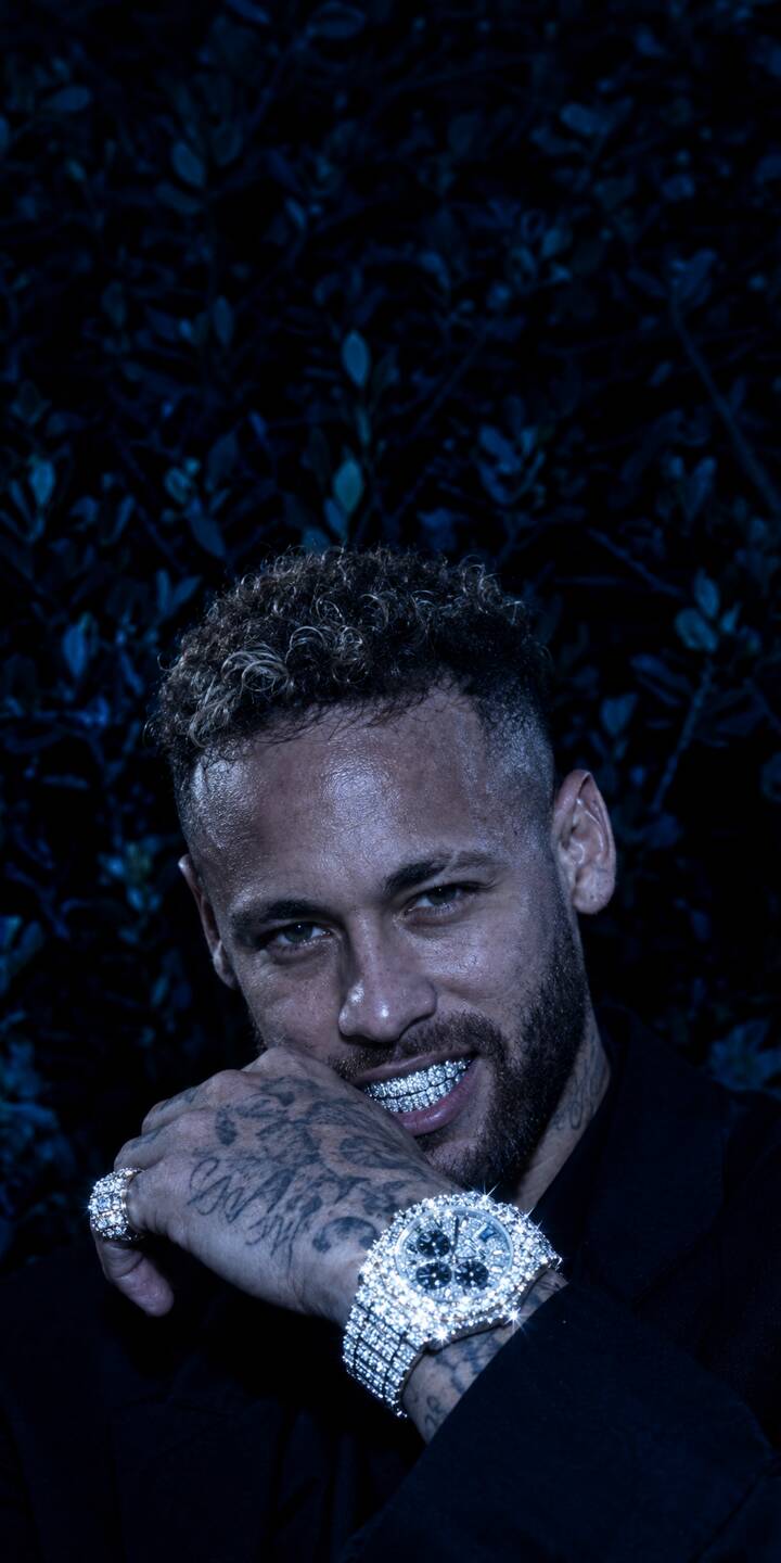 Diamond-encrusted grillz gleam on Neymar's smiling face, complemented by a dazzling diamond watch on his tattooed hand, making this 4K wallpaper for iPhone an epitome of luxurious style. This exclusive wallpaper captures his intense gaze against a dark, moody backdrop. | diamond iphone luxury wallpaper neymar grillz mobile footballer 4k wallpaper hd wallpaper neymar jr Diamond-encrusted grillz gleam on Neymar's smiling face, complemented by a dazzling diamond watch on his tattooed hand, making this 4K wallpaper for iPhone an epitome of luxurious style. This exclusive wallpaper captures his intense gaze against a dark, moody backdrop.