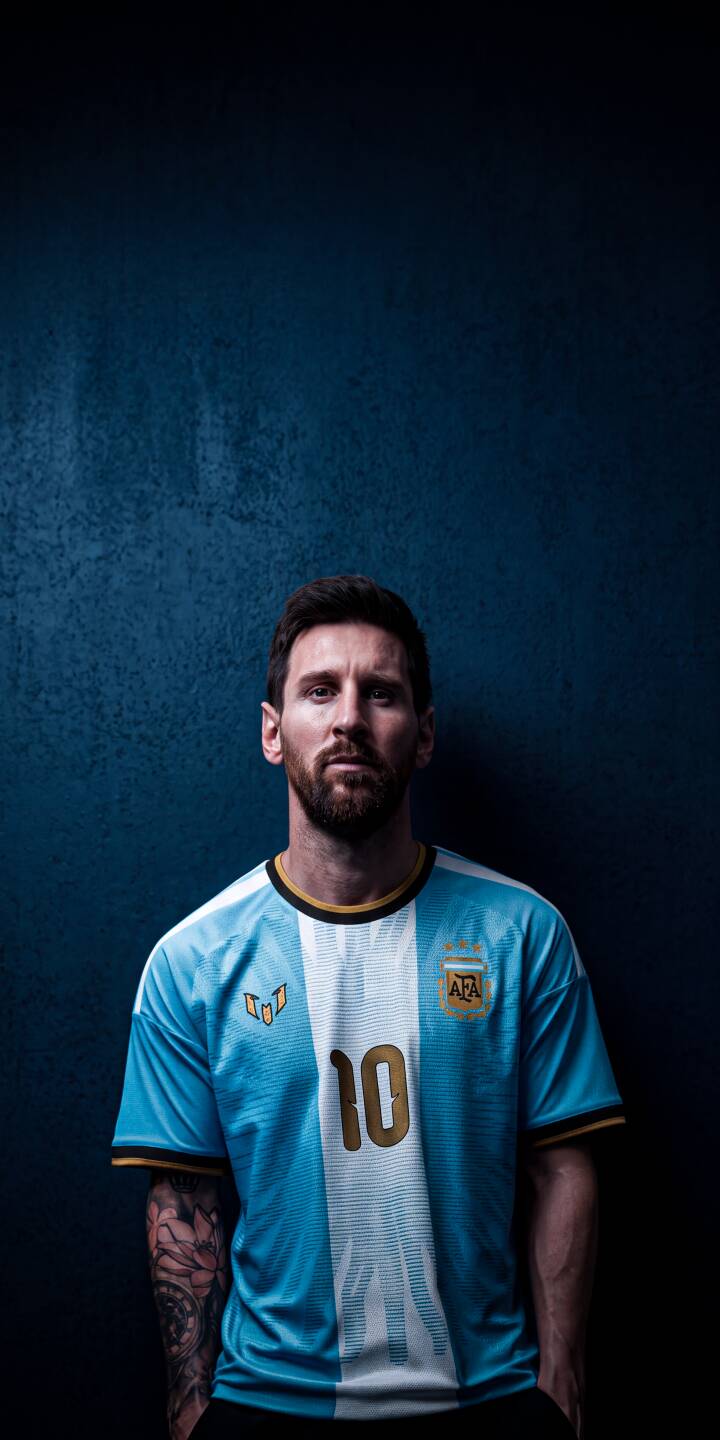 Lionel Messi's intense gaze captures attention as he sports the iconic Argentina number 10 jersey against a textured blue backdrop in this stunning 4K wallpaper. This dynamic wallpaper is perfect for any iPhone, showcasing the legendary footballer with a visible arm tattoo. | football iphone messi argentina soccer wallpaper jersey lionel messi mobile 4k wallpaper hd wallpaper blue background Lionel Messi's intense gaze captures attention as he sports the iconic Argentina number 10 jersey against a textured blue backdrop in this stunning 4K wallpaper. This dynamic wallpaper is perfect for any iPhone, showcasing the legendary footballer with a visible arm tattoo.