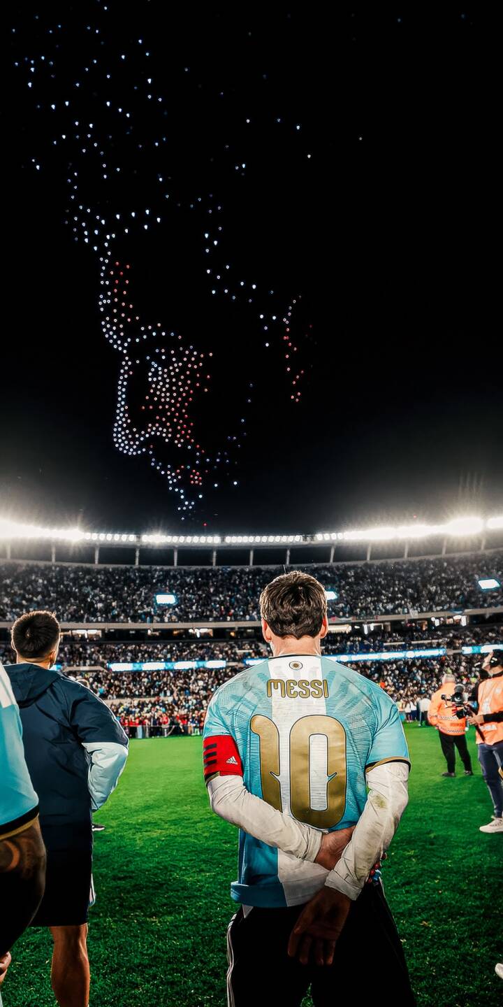 A breathtaking drone light show depicting a dynamic figure glows above a packed stadium, as football legend Lionel Messi, with his iconic number 10 jersey, gazes out at the fervent crowd in this striking 4K wallpaper — an essential iPhone wallpaper for fans. | football stadium celebration iphone messi argentina wallpaper lionel messi mobile 4k wallpaper hd wallpaper drone show A breathtaking drone light show depicting a dynamic figure glows above a packed stadium, as football legend Lionel Messi, with his iconic number 10 jersey, gazes out at the fervent crowd in this striking 4K wallpaper — an essential iPhone wallpaper for fans.