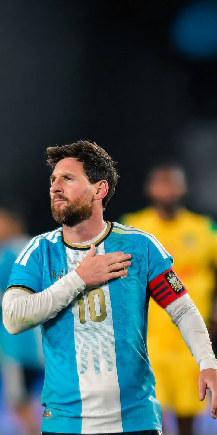 Pensive Lionel Messi stands with his hand over his heart, wearing the iconic light blue and white Argentina jersey with the captain's armband in this compelling 4K wallpaper; it's an essential iPhone wallpaper for football fans. | sports football iphone messi argentina soccer wallpaper captain lionel messi mobile 4k wallpaper hd wallpaper Pensive Lionel Messi stands with his hand over his heart, wearing the iconic light blue and white Argentina jersey with the captain's armband in this compelling 4K wallpaper; it's an essential iPhone wallpaper for football fans.