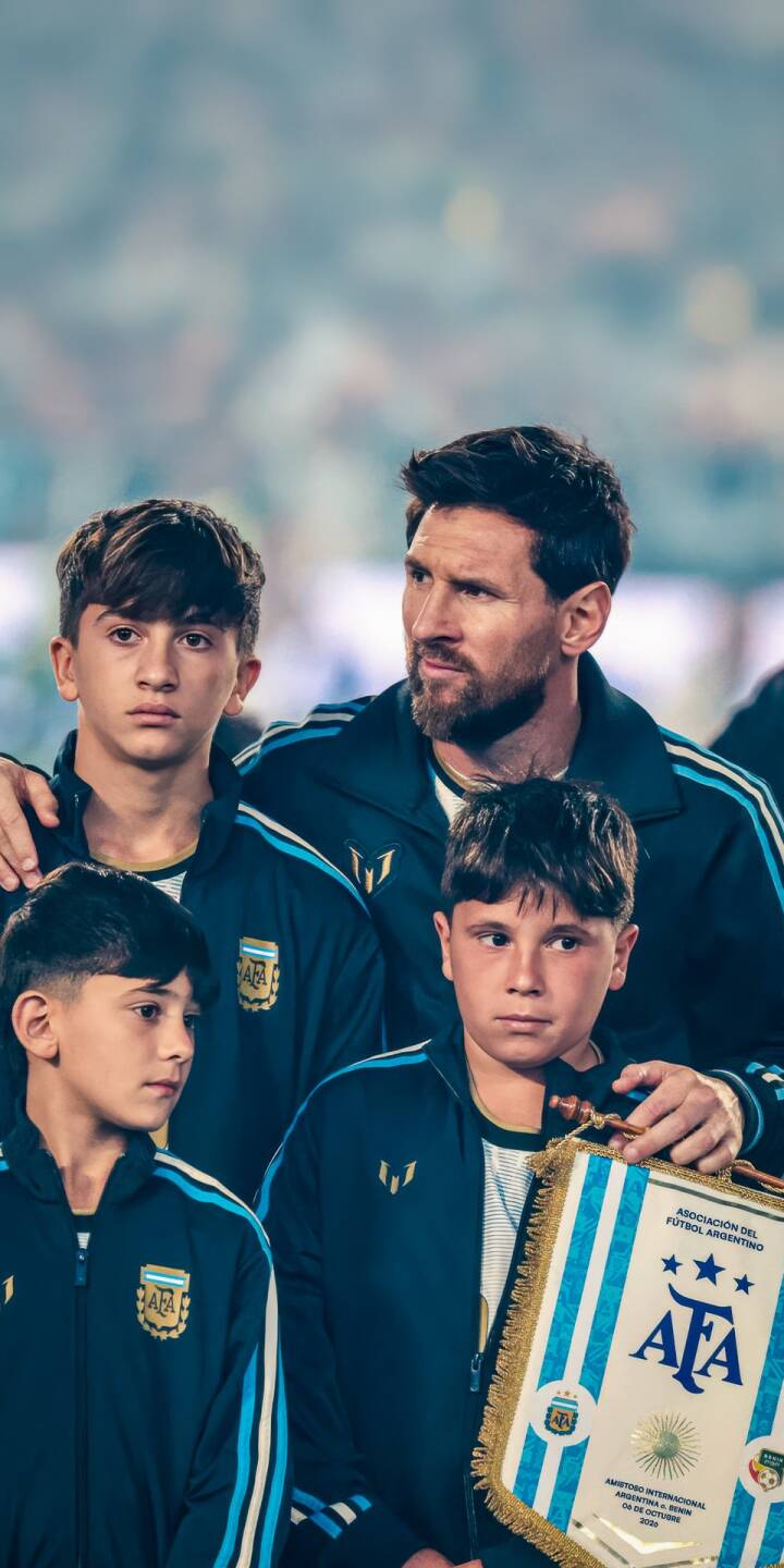 Lionel Messi's pensive gaze oversees young athletes in matching Argentina track jackets, forming an inspiring moment captured in this striking 4K wallpaper. This powerful wallpaper, perfect for iPhone, emphasizes a sense of legacy as one boy proudly displays an AFA banner, under stadium lights. | sports football iphone messi argentina soccer wallpaper lionel messi mobile 4k wallpaper hd wallpaper legacy Lionel Messi's pensive gaze oversees young athletes in matching Argentina track jackets, forming an inspiring moment captured in this striking 4K wallpaper. This powerful wallpaper, perfect for iPhone, emphasizes a sense of legacy as one boy proudly displays an AFA banner, under stadium lights.