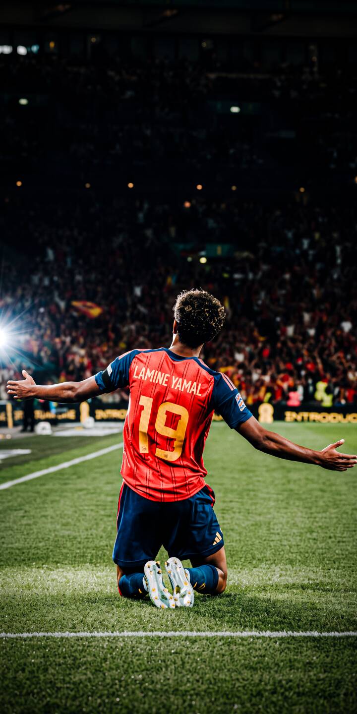 A bright stadium light shines behind Lamine Yamal as he kneels on the green pitch, arms outstretched in triumph, wearing his iconic Spain number 19 jersey. This dynamic 4K wallpaper captures the celebratory moment perfectly and makes an inspiring wallpaper for iPhone. | sports football stadium celebration iphone soccer spain wallpaper lamine yamal mobile 4k wallpaper hd wallpaper A bright stadium light shines behind Lamine Yamal as he kneels on the green pitch, arms outstretched in triumph, wearing his iconic Spain number 19 jersey. This dynamic 4K wallpaper captures the celebratory moment perfectly and makes an inspiring wallpaper for iPhone.