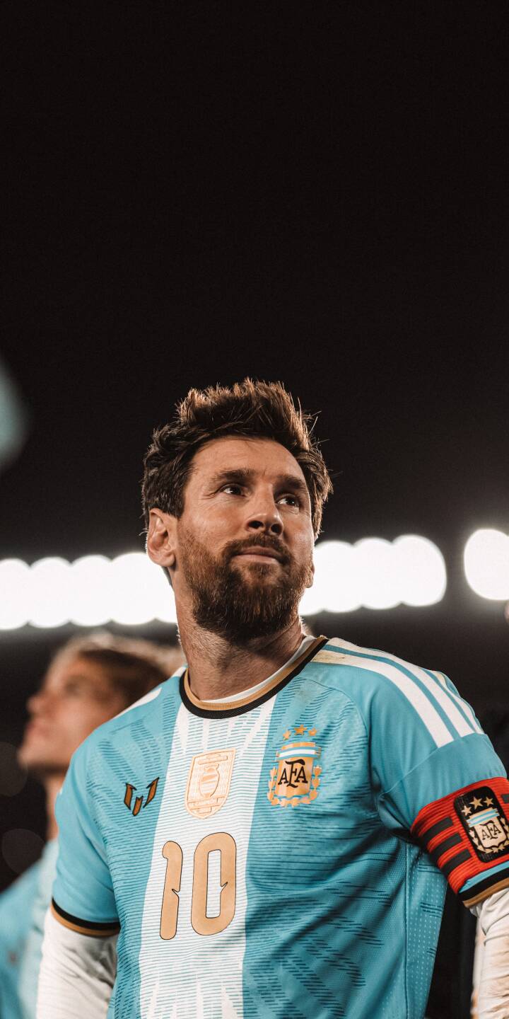 Lionel Messi wears his Argentina #10 jersey with the captain's armband, looking focused in this compelling 4K wallpaper. It's an inspiring wallpaper for any iPhone, showcasing his determined gaze against a dark stadium backdrop. | football athlete iphone messi argentina soccer wallpaper lionel messi mobile 4k wallpaper hd wallpaper number 10 Lionel Messi wears his Argentina #10 jersey with the captain's armband, looking focused in this compelling 4K wallpaper. It's an inspiring wallpaper for any iPhone, showcasing his determined gaze against a dark stadium backdrop.