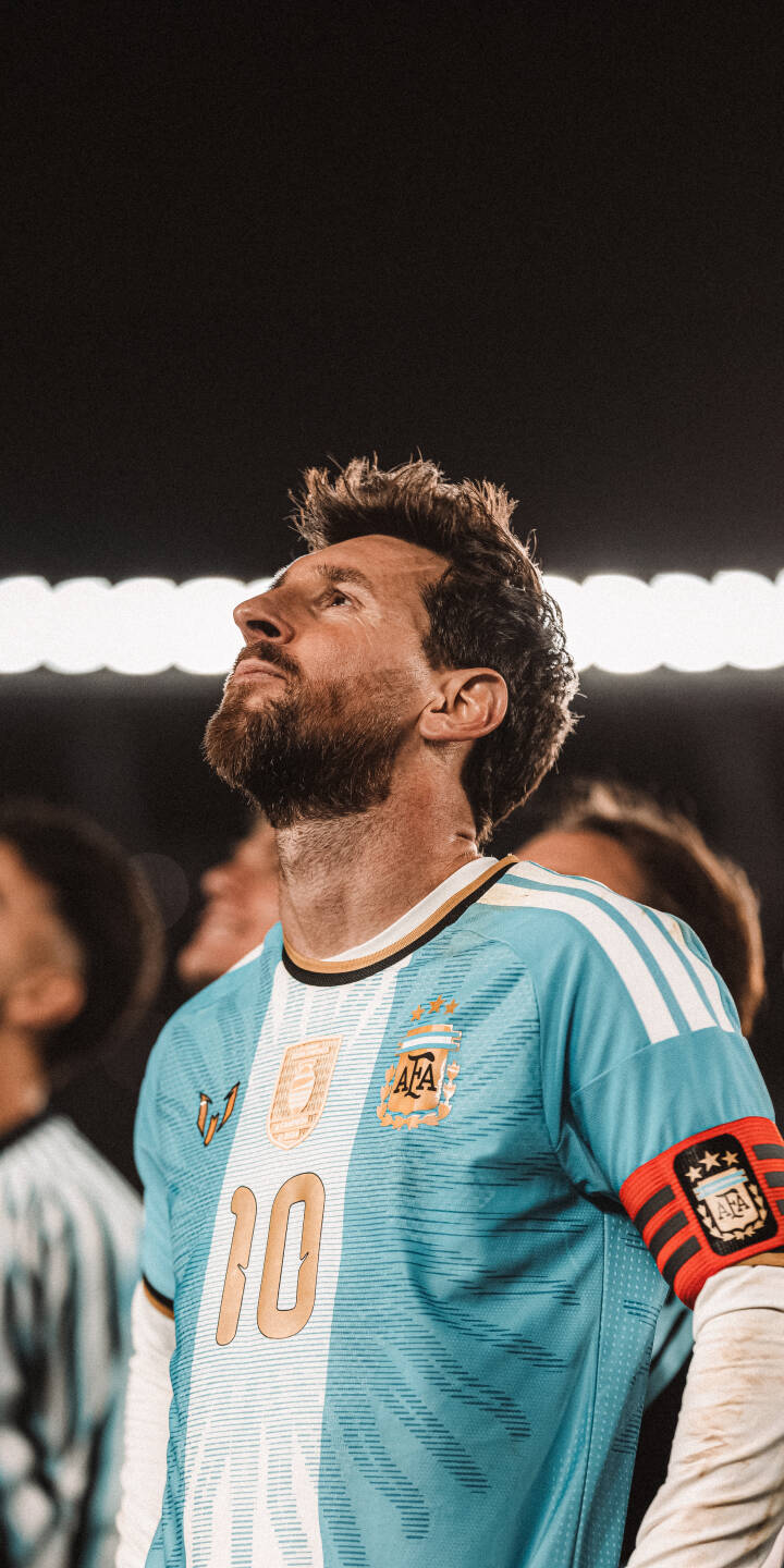 A dramatic spotlight highlights Lionel Messi's intense gaze as he looks upward, proudly wearing the iconic Argentina number 10 jersey and captain's armband in this stunning 4K wallpaper. This captivating wallpaper is perfect for any iPhone, celebrating the legendary footballer. | football iphone messi argentina soccer wallpaper captain lionel messi mobile 4k wallpaper hd wallpaper iconic A dramatic spotlight highlights Lionel Messi's intense gaze as he looks upward, proudly wearing the iconic Argentina number 10 jersey and captain's armband in this stunning 4K wallpaper. This captivating wallpaper is perfect for any iPhone, celebrating the legendary footballer.