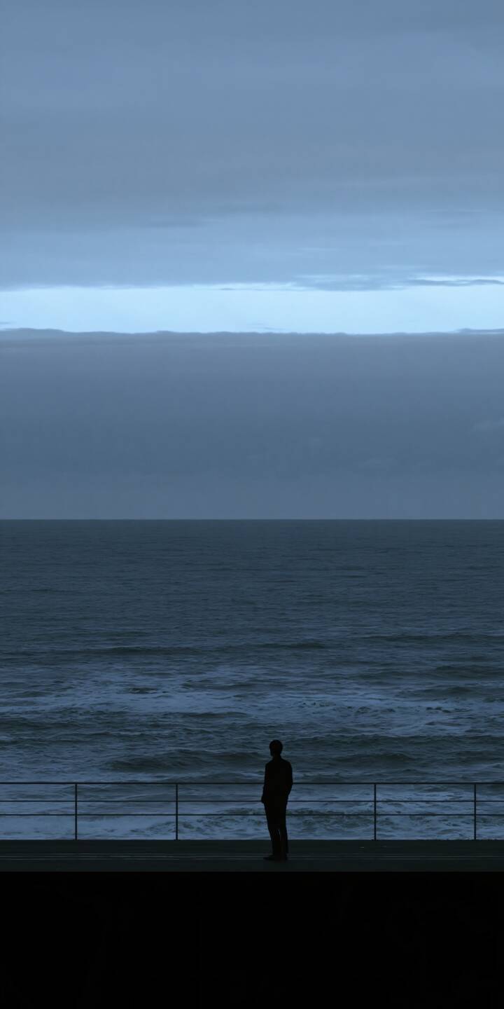 A solitary figure stands quietly along a coastal promenade, gazing toward the endless blue ocean beneath a vast, overcast sky. Layers of deep blue and muted gray clouds stretch across the horizon, while a narrow band of pale light separates the sky from the distant sea. Gentle waves roll toward the shore, creating a peaceful yet melancholic atmosphere. The minimalist composition, cool cinematic tones, and small human silhouette capture a timeless feeling of solitude, introspection, and quiet freedom beside the ocean. | blue alone ocean solitude moody A solitary figure stands quietly along a coastal promenade, gazing toward the endless blue ocean beneath a vast, overcast sky. Layers of deep blue and muted gray clouds stretch across the horizon, while a narrow band of pale light separates the sky from the distant sea. Gentle waves roll toward the shore, creating a peaceful yet melancholic atmosphere. The minimalist composition, cool cinematic tones, and small human silhouette capture a timeless feeling of solitude, introspection, and quiet freedom beside the ocean.