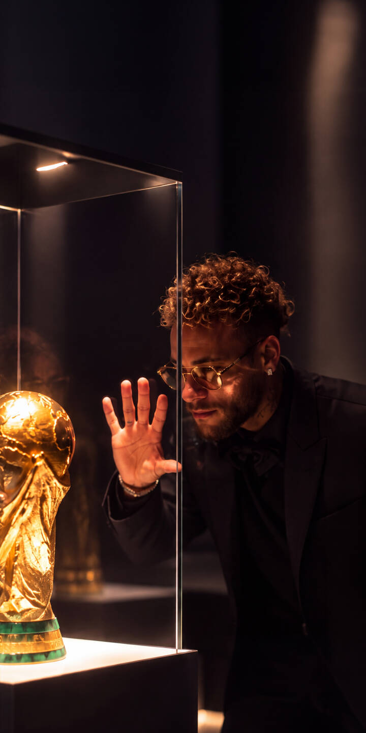 Neymar's intense gaze and outstretched hand reach towards the gleaming golden World Cup trophy displayed behind reflective glass in this stunning 4K wallpaper. This luxury-themed wallpaper, featuring the iconic football star, is a must-have for any iPhone owner. | football iphone luxury soccer wallpaper neymar golden mobile elegant 4k wallpaper hd wallpaper world cup trophy Neymar's intense gaze and outstretched hand reach towards the gleaming golden World Cup trophy displayed behind reflective glass in this stunning 4K wallpaper. This luxury-themed wallpaper, featuring the iconic football star, is a must-have for any iPhone owner.