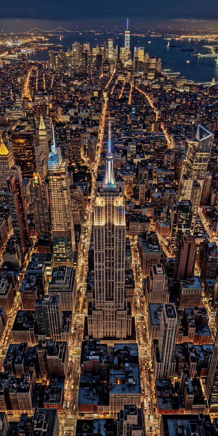 Golden lights vividly illuminate the sprawling grid of New York City's skyscrapers and streets from an impressive aerial perspective, focusing on the iconic Empire State Building. This stunning 4K wallpaper offers an expansive nocturnal view, making it a perfect wallpaper for iPhone users who love vibrant urban landscapes. | empire state building iphone wallpaper mobile aerial view new york city nyc 4k wallpaper hd wallpaper manhattan cityscape night lights Golden lights vividly illuminate the sprawling grid of New York City's skyscrapers and streets from an impressive aerial perspective, focusing on the iconic Empire State Building. This stunning 4K wallpaper offers an expansive nocturnal view, making it a perfect wallpaper for iPhone users who love vibrant urban landscapes.