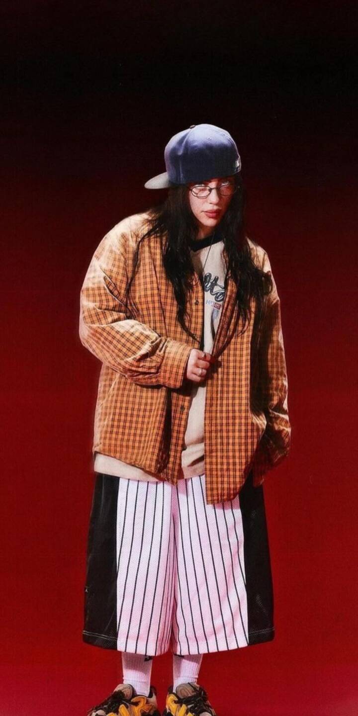 The vibrant red background highlights a person sporting a backward blue cap, stylish glasses, and an oversized plaid shirt, creating a cool urban aesthetic. This stunning 4K wallpaper is a perfect iPhone wallpaper for those who love streetwear fashion. | billie eilish The vibrant red background highlights a person sporting a backward blue cap, stylish glasses, and an oversized plaid shirt, creating a cool urban aesthetic. This stunning 4K wallpaper is a perfect iPhone wallpaper for those who love streetwear fashion.