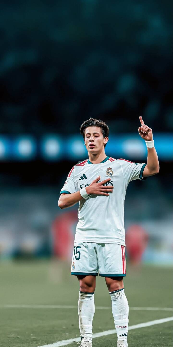 Federico Valverde, wearing his iconic white Real Madrid number 15 kit, strikes a triumphant pose with hand on chest and finger pointed skyward in this stunning 4K wallpaper. This vibrant football wallpaper for iPhone perfectly captures the essence of the pitchside emotion. | football stadium player iphone soccer real madrid wallpaper mobile 4k wallpaper hd wallpaper valverde federico valverde Federico Valverde, wearing his iconic white Real Madrid number 15 kit, strikes a triumphant pose with hand on chest and finger pointed skyward in this stunning 4K wallpaper. This vibrant football wallpaper for iPhone perfectly captures the essence of the pitchside emotion.