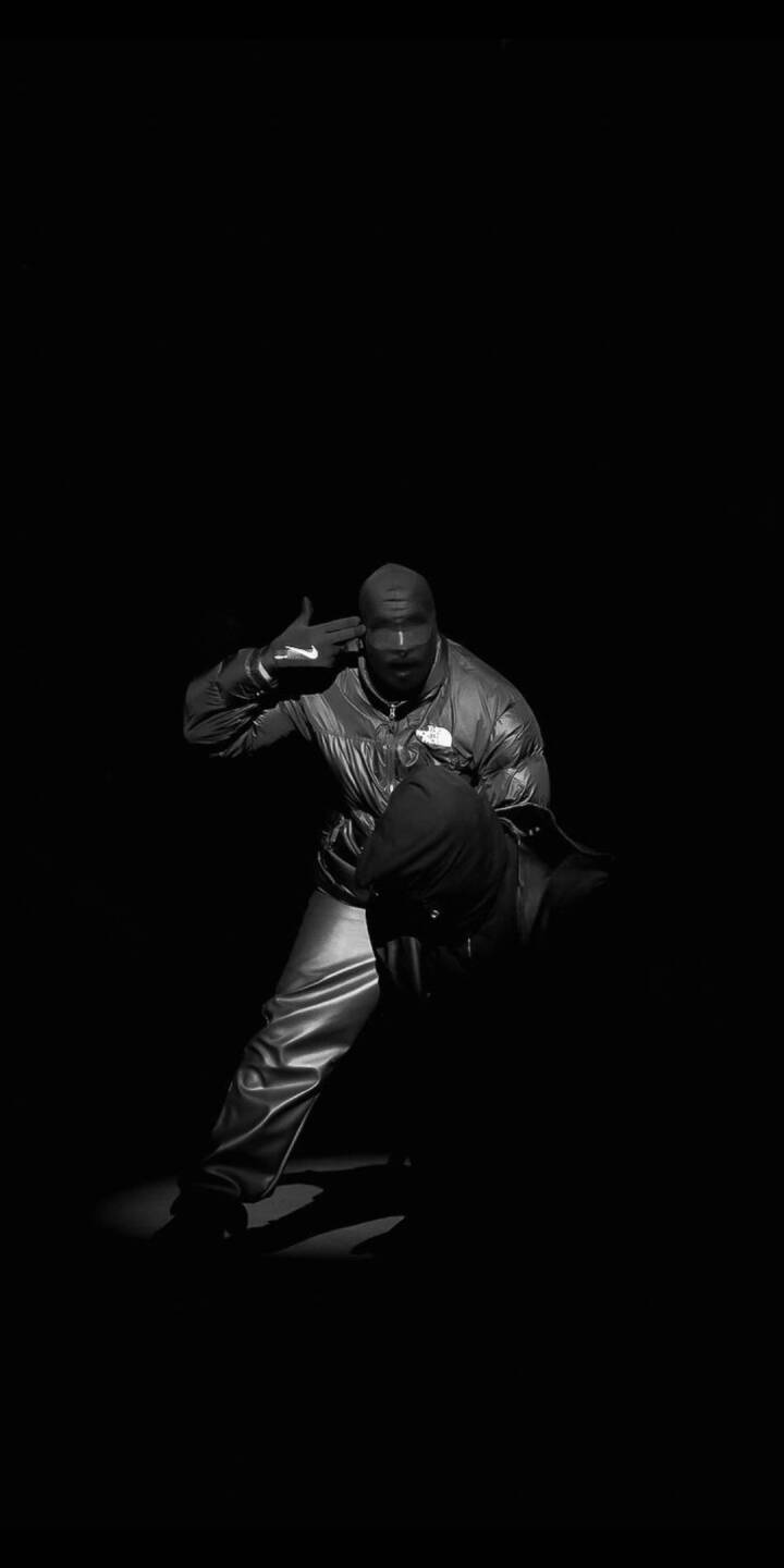 A somber grayscale scene captures a mysterious figure in a balaclava and glossy puffer jacket making a dramatic finger-gun pose against a pure black background, creating an intense 4K wallpaper perfect for your iPhone. This compelling and dark wallpaper is ideal for fans of edgy, monochromatic aesthetics. | artist A somber grayscale scene captures a mysterious figure in a balaclava and glossy puffer jacket making a dramatic finger-gun pose against a pure black background, creating an intense 4K wallpaper perfect for your iPhone. This compelling and dark wallpaper is ideal for fans of edgy, monochromatic aesthetics.