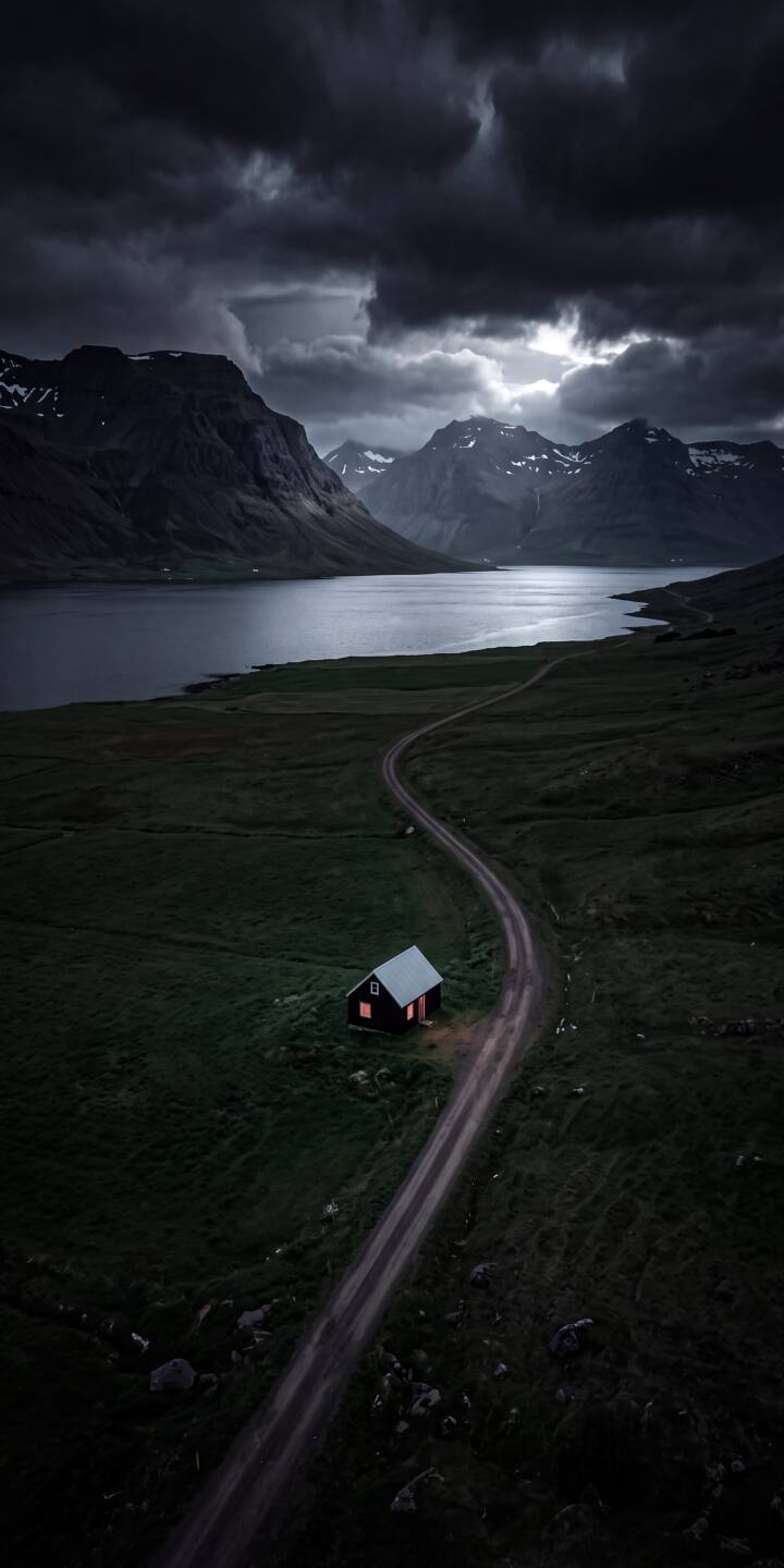 The lone cabin's warm glowing windows offer a stark contrast to the dramatic, dark storm clouds looming over the fjord in this captivating 4K landscape wallpaper, making it an evocative wallpaper for iPhone. | aesthetic landscape dark iphone mountains wallpaper mobile moody cabin 4k wallpaper hd wallpaper fjord The lone cabin's warm glowing windows offer a stark contrast to the dramatic, dark storm clouds looming over the fjord in this captivating 4K landscape wallpaper, making it an evocative wallpaper for iPhone.