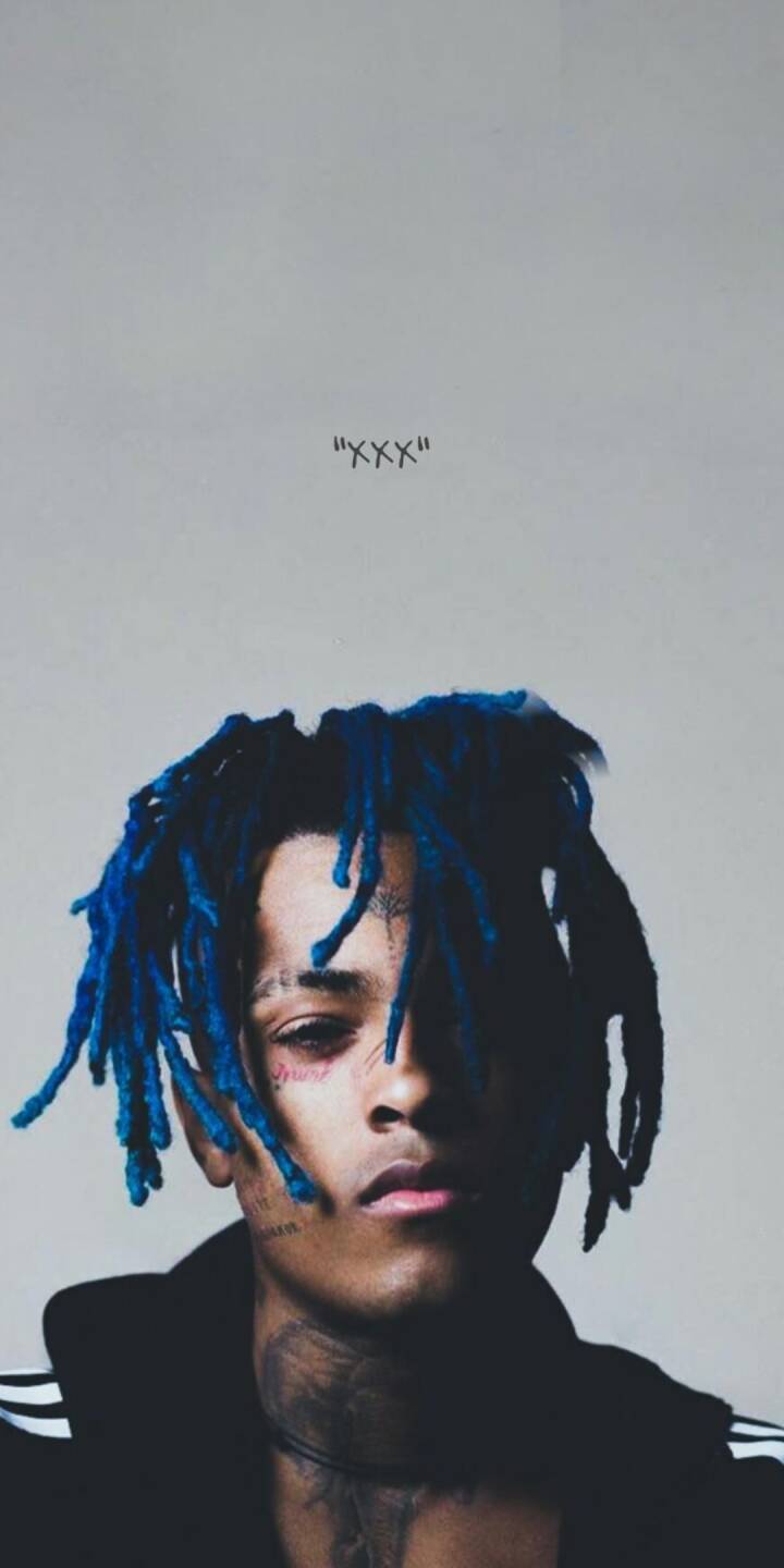 The vibrant blue dreadlocks of XXXTentacion stand out against the clean background in this striking 4K wallpaper, featuring his distinctive face tattoos. This essential wallpaper for iPhone perfectly captures the artist's intense gaze. | artist The vibrant blue dreadlocks of XXXTentacion stand out against the clean background in this striking 4K wallpaper, featuring his distinctive face tattoos. This essential wallpaper for iPhone perfectly captures the artist's intense gaze.