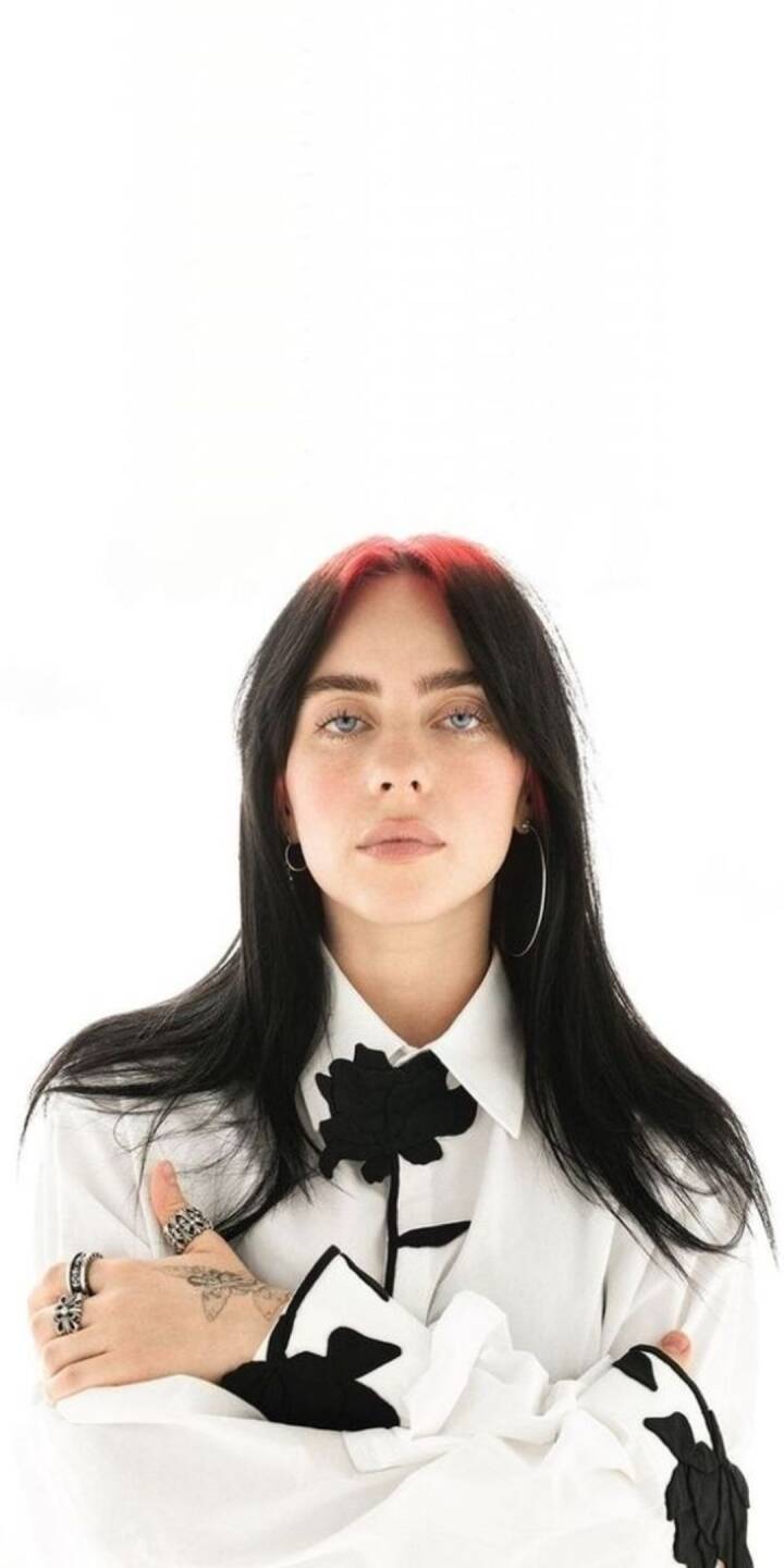 Billie Eilish's striking red roots contrast with her dark hair and piercing gaze in this artistic 4K wallpaper, featuring her unique black floral shirt design — a must-have wallpaper for iPhone. | artist Billie Eilish's striking red roots contrast with her dark hair and piercing gaze in this artistic 4K wallpaper, featuring her unique black floral shirt design — a must-have wallpaper for iPhone.
