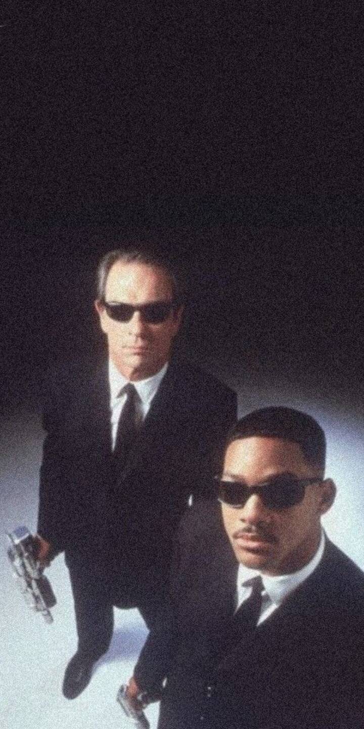 Serious expressions and matching black suits define Agents J and K as they gaze upward, holding their sleek chrome weapons in this compelling 4K wallpaperโan essential wallpaper for iPhone users who love the Men in Black series. | artist Serious expressions and matching black suits define Agents J and K as they gaze upward, holding their sleek chrome weapons in this compelling 4K wallpaperโan essential wallpaper for iPhone users who love the Men in Black series.