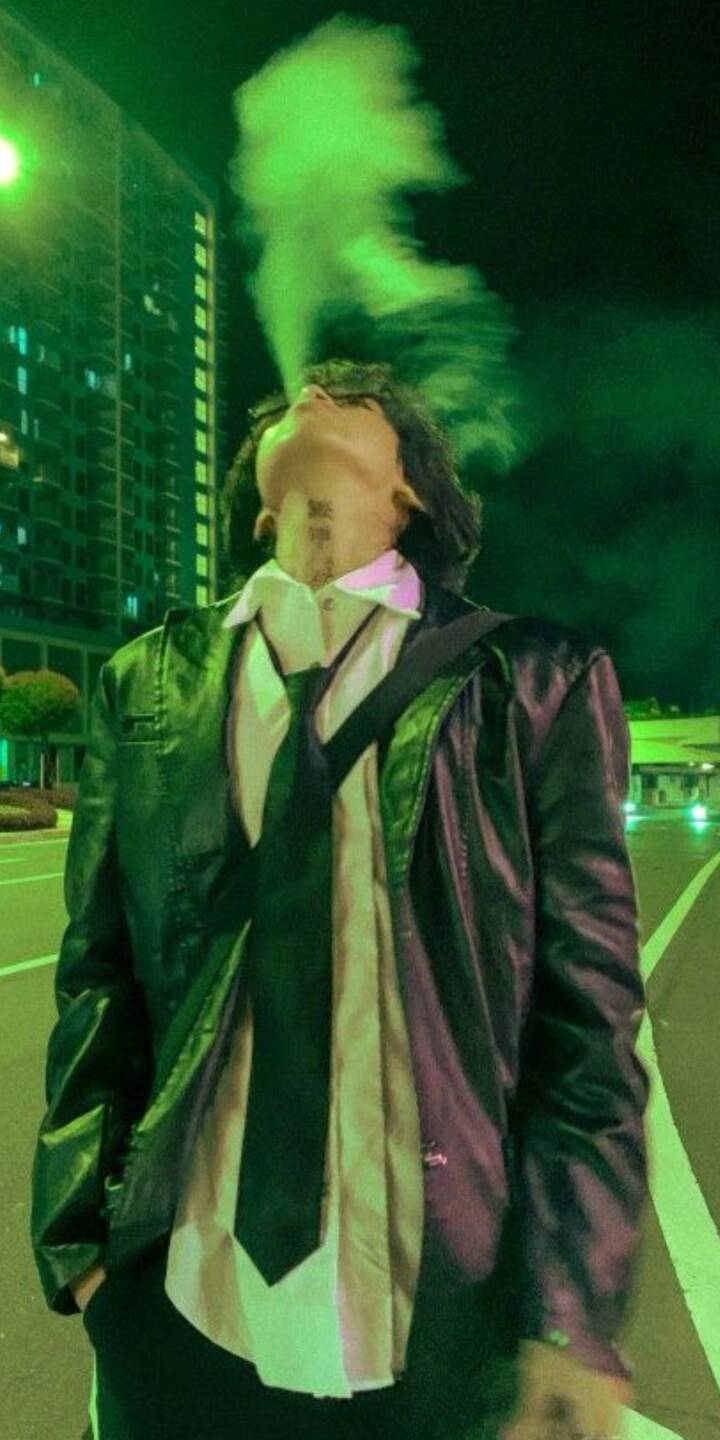 Green vapor billows dramatically from a mysterious figure's mouth, illuminated by neon city lights in this striking 4K wallpaper — an edgy mobile wallpaper for iPhone featuring an urban night aesthetic. | artist Green vapor billows dramatically from a mysterious figure's mouth, illuminated by neon city lights in this striking 4K wallpaper — an edgy mobile wallpaper for iPhone featuring an urban night aesthetic.