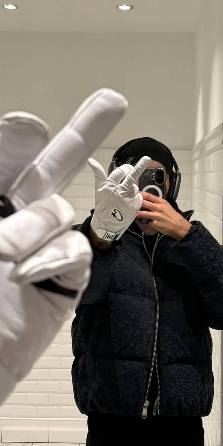 A person in white gloves makes a distinctive hand gesture while capturing a stylish mirror selfie, framed by a sleek black puffer jacket and headphones in this sharp 4K wallpaper. This dynamic, urban-inspired image offers an edgy and modern wallpaper for iPhone users. | artist A person in white gloves makes a distinctive hand gesture while capturing a stylish mirror selfie, framed by a sleek black puffer jacket and headphones in this sharp 4K wallpaper. This dynamic, urban-inspired image offers an edgy and modern wallpaper for iPhone users.
