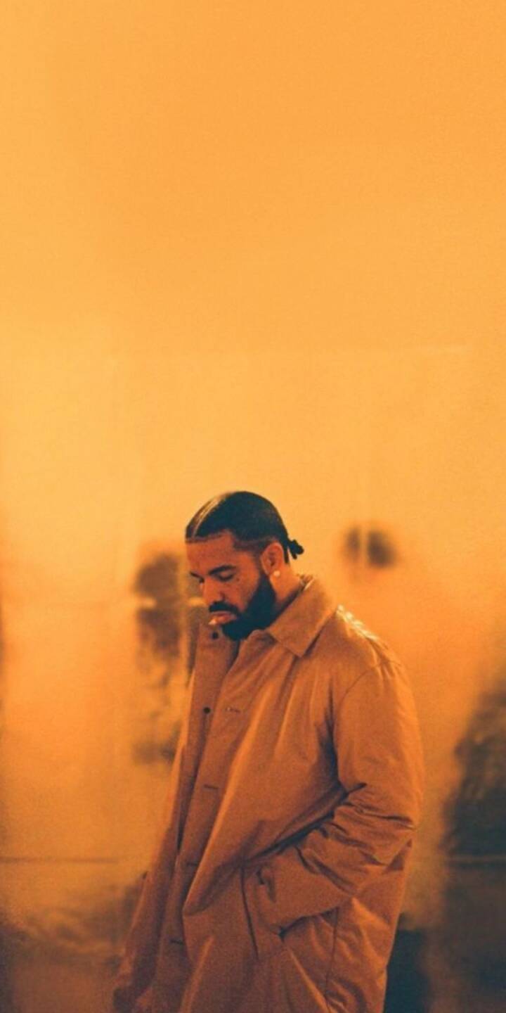 A captivating amber glow envelops a pensive Drake, shown with a cigarette in his mouth and donning a stylish, muted-tone coat in this striking 4K wallpaper. This immersive Drake wallpaper is perfectly optimized for iPhone screens. | artist A captivating amber glow envelops a pensive Drake, shown with a cigarette in his mouth and donning a stylish, muted-tone coat in this striking 4K wallpaper. This immersive Drake wallpaper is perfectly optimized for iPhone screens.