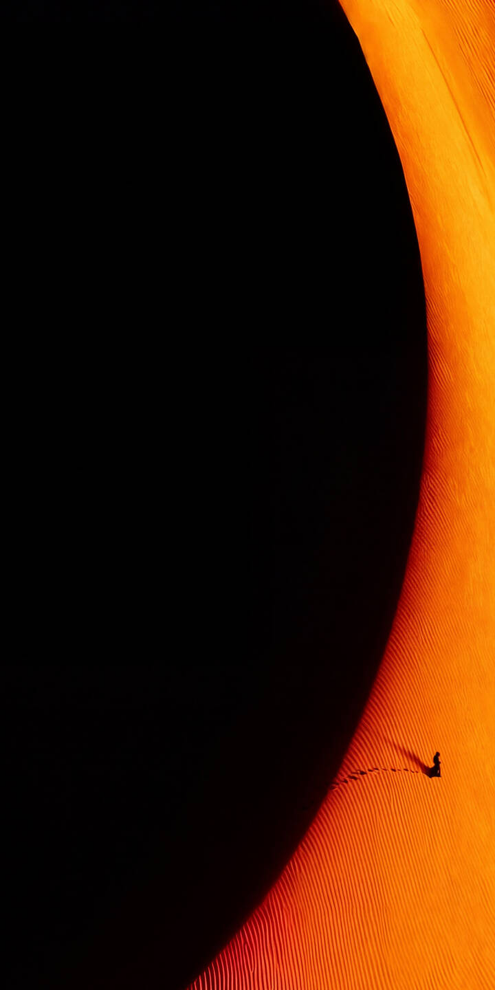 The dramatic curve of an orange desert dune sharply contrasts with a deep black void in this mesmerizing 4K wallpaper, showcasing a tiny, solitary figure leaving tracks along its rhythmic ripples — a perfect minimalist wallpaper for iPhone. | orange desert sand iphone nature minimalist dune wallpaper mobile solitude 4k wallpaper hd wallpaper The dramatic curve of an orange desert dune sharply contrasts with a deep black void in this mesmerizing 4K wallpaper, showcasing a tiny, solitary figure leaving tracks along its rhythmic ripples — a perfect minimalist wallpaper for iPhone.