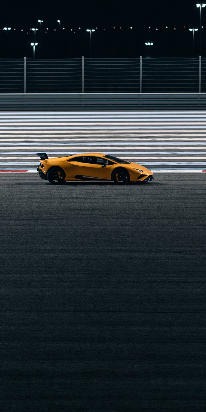 A striking yellow supercar captured in perfect side profile on a quiet racing circuit at night. Bright track markings, distant floodlights, and dark asphalt emphasize the car's aggressive silhouette. The contrast between vibrant yellow and deep black creates a clean, sporty, and sophisticated automotive wallpaper. | sports car race track lamborghini minimalist yellow supercar A striking yellow supercar captured in perfect side profile on a quiet racing circuit at night. Bright track markings, distant floodlights, and dark asphalt emphasize the car's aggressive silhouette. The contrast between vibrant yellow and deep black creates a clean, sporty, and sophisticated automotive wallpaper.