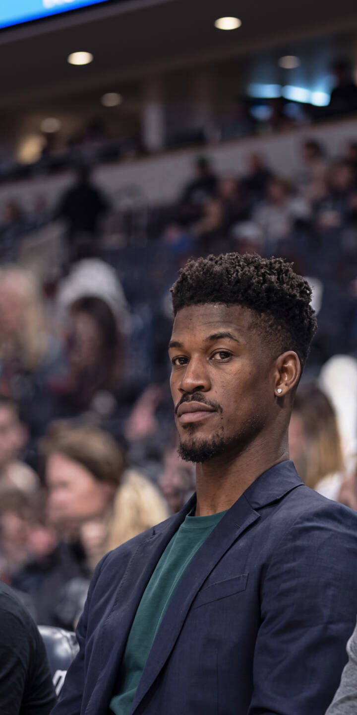 Jimmy Butler's intense gaze captures attention as he sits composed in a stylish dark blue blazer and green shirt. This striking 4K wallpaper for iPhone is a perfect fan wallpaper, highlighting his distinct look amidst a blurred crowd. | basketball nba portrait athlete iphone wallpaper jimmy butler mobile miami heat 4k wallpaper hd wallpaper dapper Jimmy Butler's intense gaze captures attention as he sits composed in a stylish dark blue blazer and green shirt. This striking 4K wallpaper for iPhone is a perfect fan wallpaper, highlighting his distinct look amidst a blurred crowd.