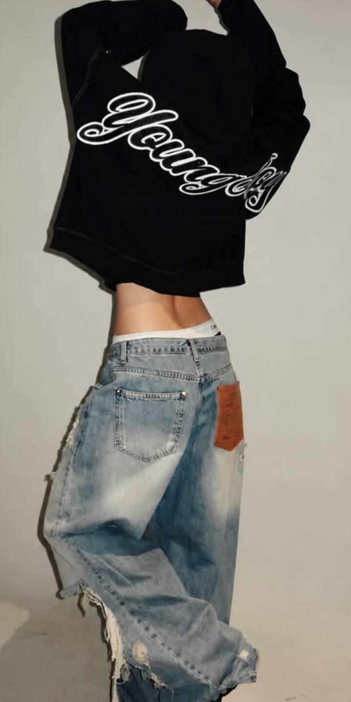 The stylish 'Younger' script on a black cropped hoodie highlights a dynamic pose, paired with distinct ripped baggy jeans and an exposed midriff in this aesthetic 4K wallpaper — a perfect streetwear fashion wallpaper for iPhone users. | artist The stylish 'Younger' script on a black cropped hoodie highlights a dynamic pose, paired with distinct ripped baggy jeans and an exposed midriff in this aesthetic 4K wallpaper — a perfect streetwear fashion wallpaper for iPhone users.