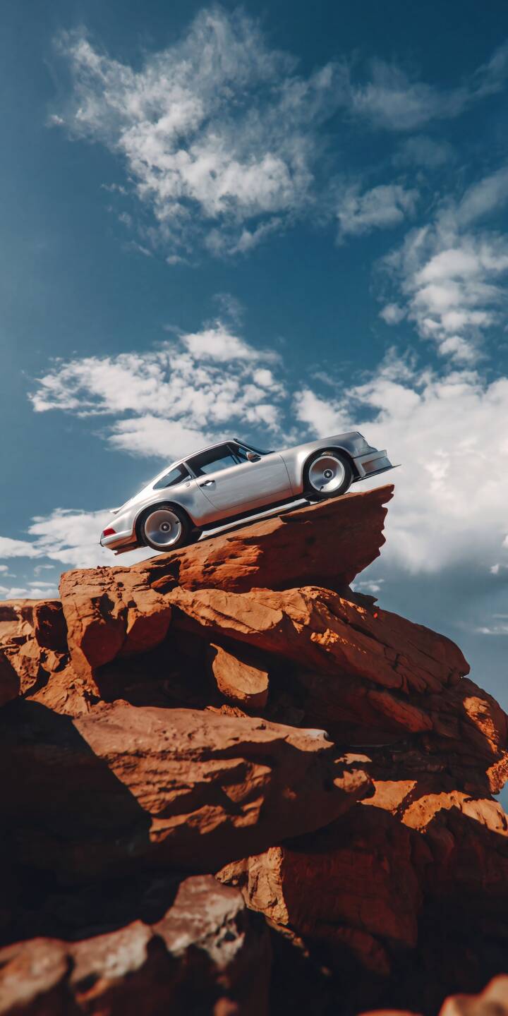 A gleaming silver Porsche balances impossibly on a vibrant red rock formation under a bright blue, cloudy sky in this stunning 4K wallpaper, making it an epic choice for an iPhone background. This unique automotive wallpaper captures a sense of adventurous luxury. | sports car desert cliff iphone porsche wallpaper mobile porsche 911 4k wallpaper hd wallpaper automotive classic car A gleaming silver Porsche balances impossibly on a vibrant red rock formation under a bright blue, cloudy sky in this stunning 4K wallpaper, making it an epic choice for an iPhone background. This unique automotive wallpaper captures a sense of adventurous luxury.