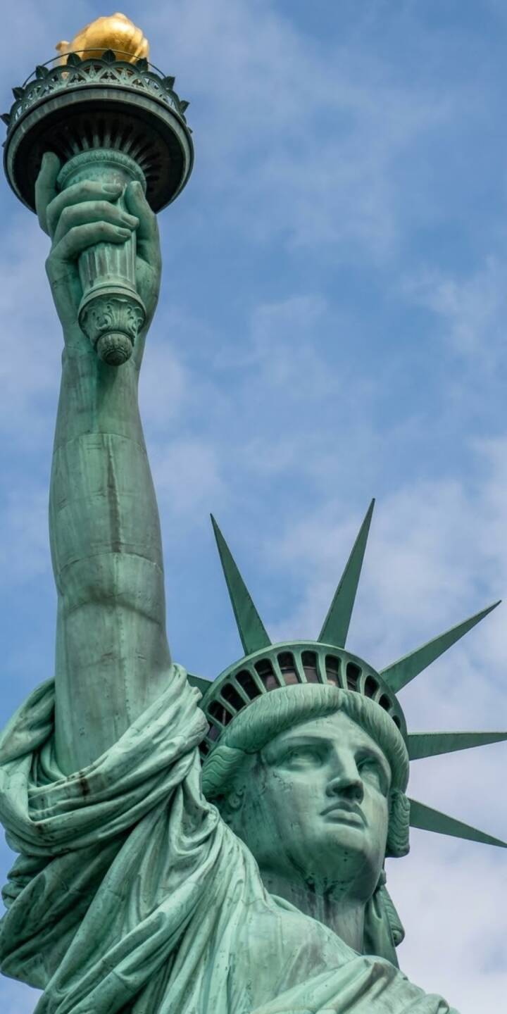 The majestic copper-green patina of the Statue of Liberty is beautifully captured against a clear blue sky, her golden torch held high in this striking 4K wallpaper. This iconic New York landmark makes a profound statement on any iPhone as a lock screen wallpaper. | art The majestic copper-green patina of the Statue of Liberty is beautifully captured against a clear blue sky, her golden torch held high in this striking 4K wallpaper. This iconic New York landmark makes a profound statement on any iPhone as a lock screen wallpaper.