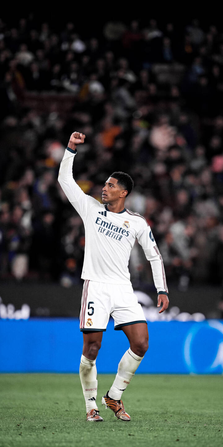 Jude Bellingham pumps his fist in triumph, celebrating on the pitch while wearing his white Real Madrid jersey number 5 in this striking 4K wallpaper. This vibrant wallpaper captures the electrifying match-day atmosphere and is perfect for personalizing your iPhone. | football athletic celebration iphone soccer real madrid wallpaper jude bellingham bellingham mobile 4k wallpaper hd wallpaper Jude Bellingham pumps his fist in triumph, celebrating on the pitch while wearing his white Real Madrid jersey number 5 in this striking 4K wallpaper. This vibrant wallpaper captures the electrifying match-day atmosphere and is perfect for personalizing your iPhone.