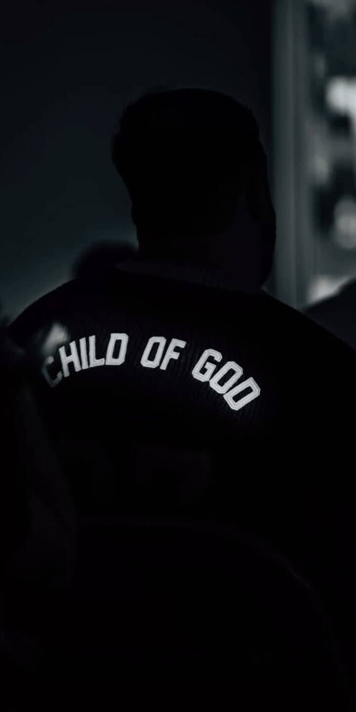 The bold, reflective "CHILD OF GOD" text glows brightly on the back of a dark jacket worn by a silhouetted figure, creating a mysterious 4K wallpaper for your iPhone. This minimalist aesthetic makes for an impactful wallpaper. | jesus The bold, reflective "CHILD OF GOD" text glows brightly on the back of a dark jacket worn by a silhouetted figure, creating a mysterious 4K wallpaper for your iPhone. This minimalist aesthetic makes for an impactful wallpaper.