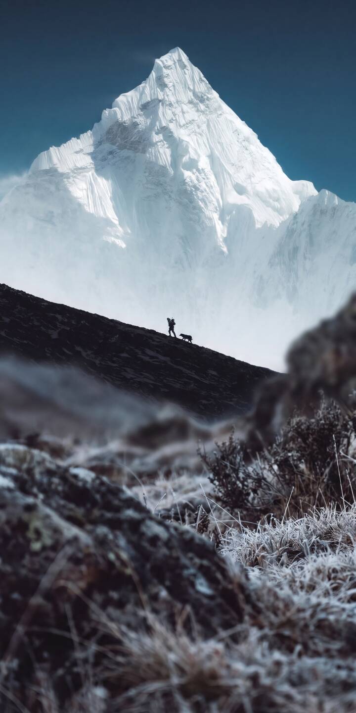 A towering white mountain peak dominates the horizon as a lone person and their dog trek across a dark, frosted slope below in this breathtaking 4K wallpaper. This majestic landscape offers a serene wallpaper for iPhone, perfect for nature lovers seeking adventure. | landscape snow peak mountain iphone nature wallpaper mobile 4k wallpaper hd wallpaper hiker adventure A towering white mountain peak dominates the horizon as a lone person and their dog trek across a dark, frosted slope below in this breathtaking 4K wallpaper. This majestic landscape offers a serene wallpaper for iPhone, perfect for nature lovers seeking adventure.