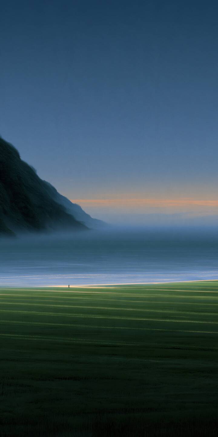 Endless green fields meet a misty coastline under an expansive blue sky. A tiny solitary figure adds a sense of freedom and peaceful isolation. | minimalist mist solitude green fields coastline Endless green fields meet a misty coastline under an expansive blue sky. A tiny solitary figure adds a sense of freedom and peaceful isolation.
